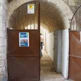 Qui infatti � collocata una pesante porta in ferro marrone inquadrata da un�arcata litica...